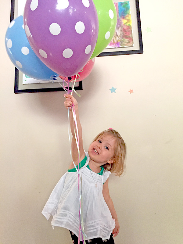 Image: A small child holding a bunch of helium-filled ballons