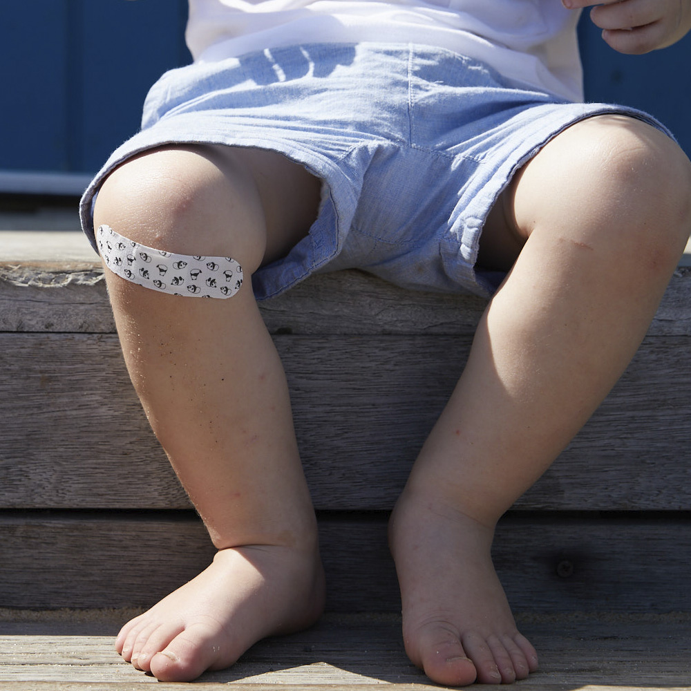 Image: toddler sitting down with a bandaid on their knee