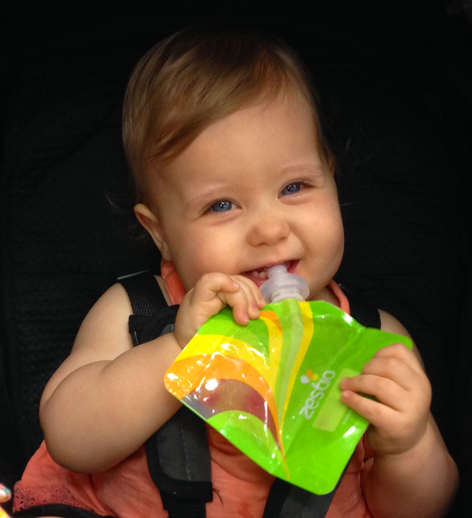 Image: Baby with a zestio food pouch feeding herself