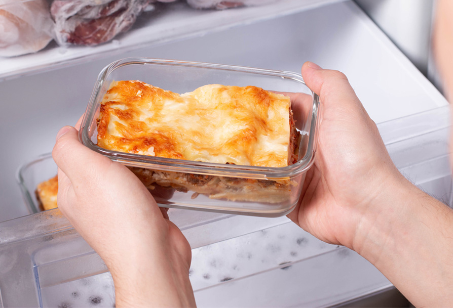 Image: lasagne in glass container going in the freezer